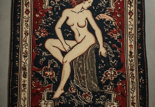 A rectangular rug with intricate patterns and a central depiction of a nude woman