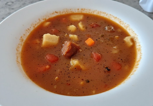 A hearty stew served in a wide, shallow white bowl