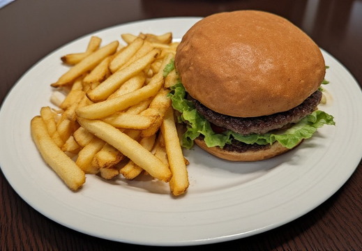 A burger and fries, is presented on a white plate