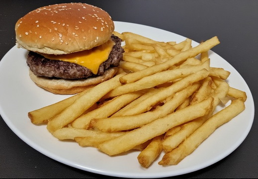 A cheeseburger and a generous portion of french fries served on a white plate