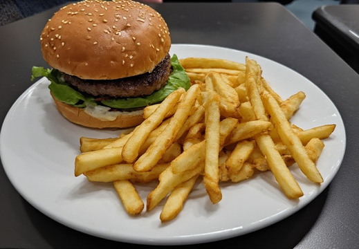 A white plate, hamburger and a serving of french fries. 