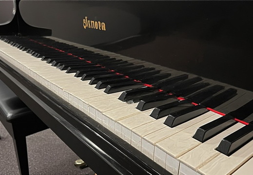 A close-up, low-angle view of the keyboard of a grand piano