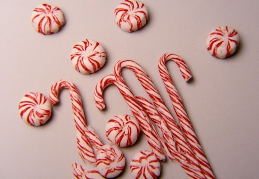 Peppermint candies and candy canes scattered across a light gray surface