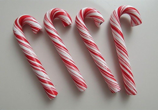 Four candy canes arranged diagonally across a plain white surface.