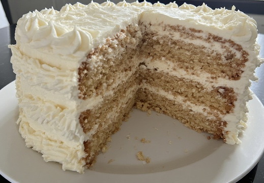 A whole cake, with a slice removed, sits on a white plate