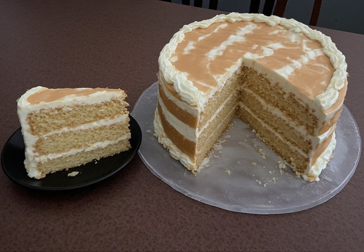 A slice of cake is presented on a small, black, oval-shaped plate.
