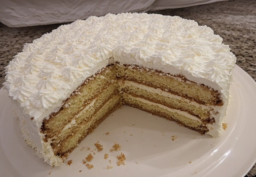 A whole cake with a slice removed on a white plate