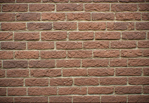 A wall of reddish-brown hue bricks