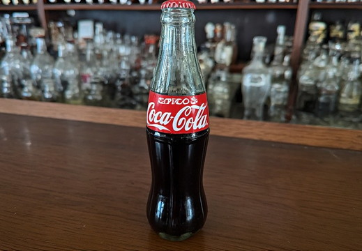 A vintage glass bottle of Coca-Cola is prominently displayed in the foreground