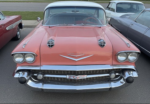 A front-facing, eye-level, medium shot of a vintage pink Chevrolet