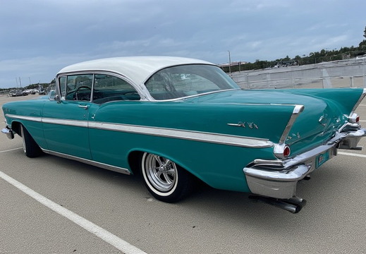 A vibrant, teal-colored vintage Chevrolet Bel Air coupe from the late 1950s, specifically likely a 1957 model