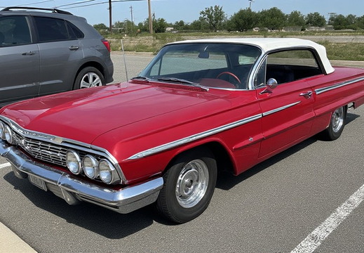 A vibrant red classic convertible parked on an asphalt surface.