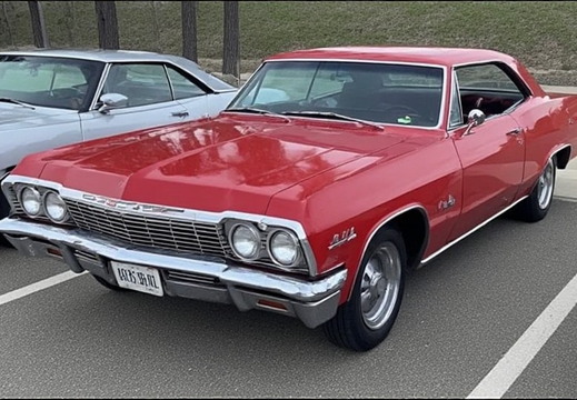 Image of a vintage red Chevrolet Impala parked in an outdoor lot
